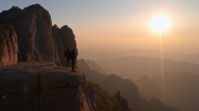 Two people standing on a cliff edge watching a beautiful sunset video