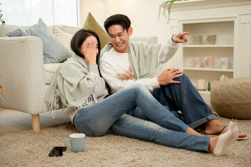 Obraz premium Couple Enjoying a Movie Night at Home With Snacks and Cozy Blankets