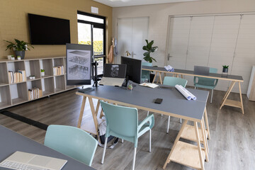 Central trestle desk holding laptop, smartphone and monitor arm displaying floor plans in studio © wavebreak3
