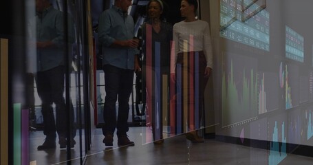 Walking team talking in office corridor with glass partitions, charts, wearing business attire