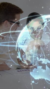 Rising holo globe urging colleagues pointing, noting charts at meeting table for deck in white tops