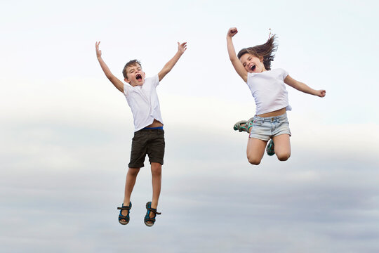 Happy carefree Boy and girl jumping in the air screaming and shouting