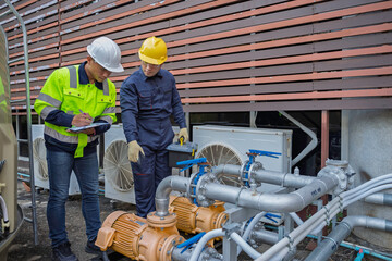 Two professional engineers inspecting industrial air conditioning system outside. Construction...