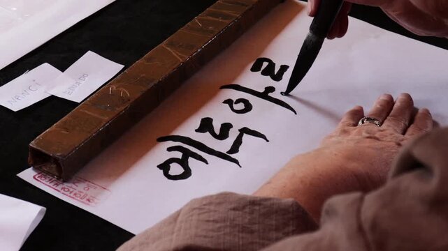 A person writing with a brush in the Korean language.