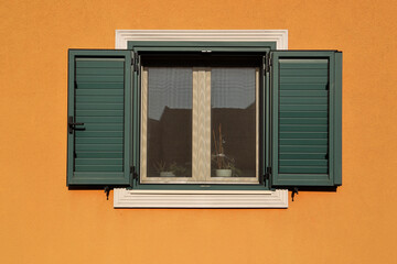 mosquito net Green pvc louvered window shutters Orange painted exterior concrete plaster in stucco wall Front view Zemun district Belgrade Serbia