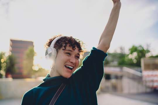 Close-up of a joyful young woman with headphones and smartphone, laughing while listening. Captures spontaneous emotional response in a mobile-first digital world.