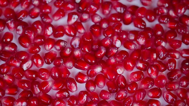 Juicy pomegranate seeds closeup shot. Reflective surface showcases vibrant seed clusters. Cinematic style focusing on fresh pomegranate seeds shimmering under bright light