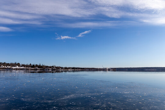 Wide view of the shoreline of Penobscot Bay in Maine showing houses and a commercial pier in the winter.