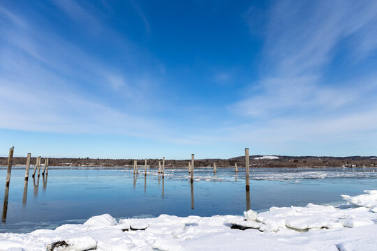 Blue sky and clouds above old wood piling in Penobscot Bay in Maine in the winter.