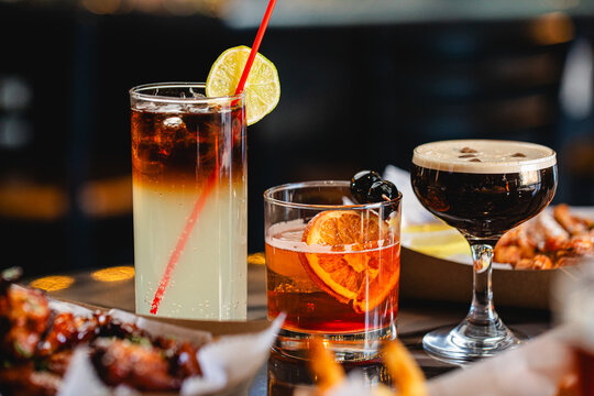 Dark and Stormy, Manhattan, Espresso Martini served together on a table at a modern restaurant and bar