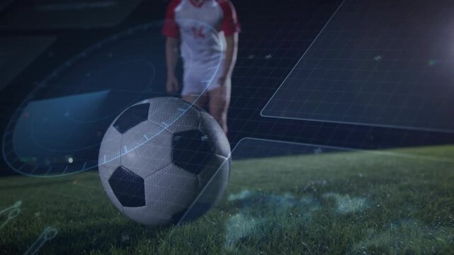Soccer player running up and kicking ball on night pitch, holographic HUD tracking shot toward goal