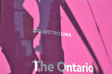 Naklejka premium abstract shadows and reflections on pink laminate hoarding with Metrolinx logo sign and The Ontario (Line) at Spadina and Queen, Toronto