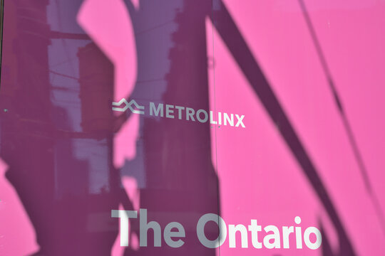 abstract shadows and reflections on pink laminate hoarding with Metrolinx logo sign and The Ontario (Line) at Spadina and Queen, Toronto