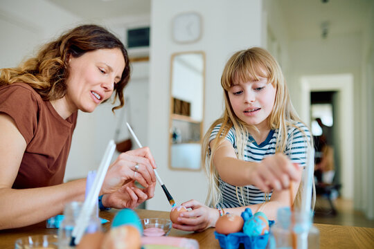 Mother and daughter enjoy creative activity preparing for Easter with colorful painted eggs, fostering family bonding at home