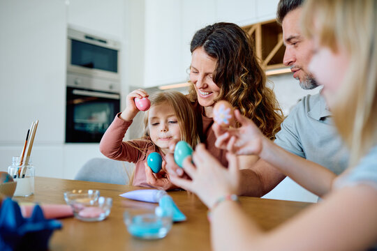 Happy family bonding while painting and decorating colorful Easter eggs together at home, preparing for the holiday celebration