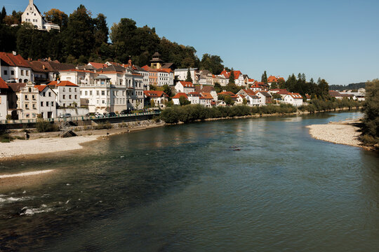 A scenic wide shot of the Enns river flowing past historic Austrian townhouses and lush greenery in Steyr, Upper Austria. Stock photo