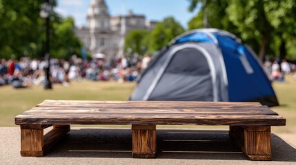 Obraz premium Wooden table top in a summer setting with a camping tent and grass field for a product display concept, mock-up template design, and bokeh effect