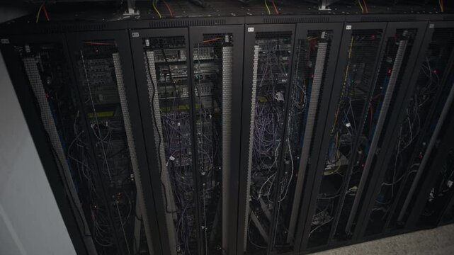 Establishing high angle view shot of server rack row with network cables and blinking hardware indicators inside modern data center corridor