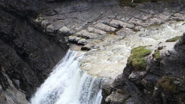 Primer plano de una cascada de agua cristalina fluyendo sobre rocas escarpadas en un entorno natural salvaje y sereno.