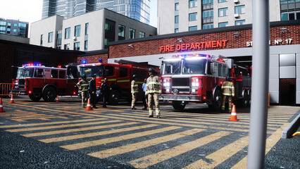 Fire station. A firefighter stands next to a fire engine. Fire trucks, their lights on, are ready to go. 3d rendering. © 3D motion