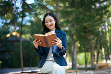 Fototapeta premium Young asian business woman enjoying reading book outdoors