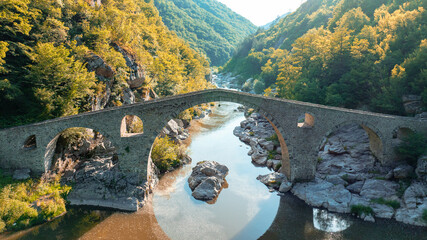 Devils Bridge Bulgaria aerial drone shot Rhodope mountains summer. Ancient ottoman stone architecture Arda river canyon landmark. Scenic mountain landscape forest hills travel destination Balkan mount