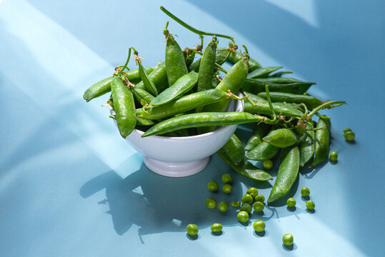 Green peas on a blue background, spring vegetables