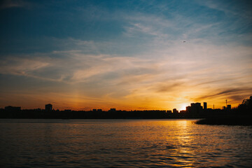 Naklejka premium Beautiful sunset view in a city with water surrounding the city in front with the shape of the sunset