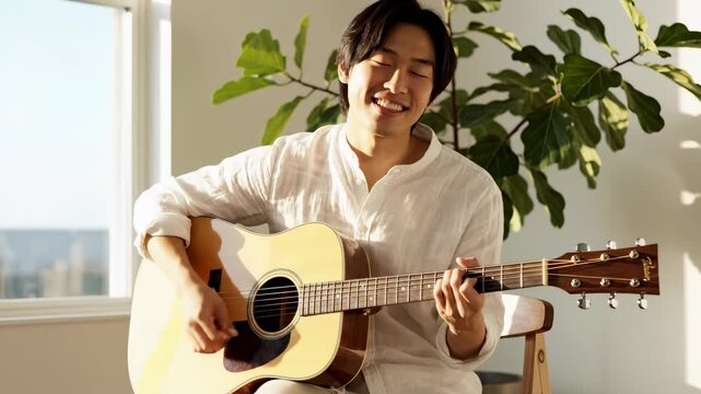Musician plays guitar while smiling in bright room filled with plants. Large windows allow sunlight to fill space. Concept of music, entertainment, creativity, and performance