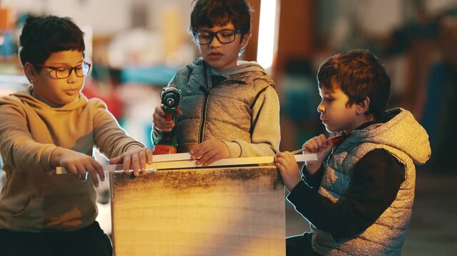 Young boys collaborating on woodworking project with drill