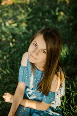 Fototapeta premium Portrait of young woman sitting on grass in summer nature