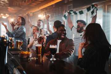 Diverse group of friends cheering sports at a bar