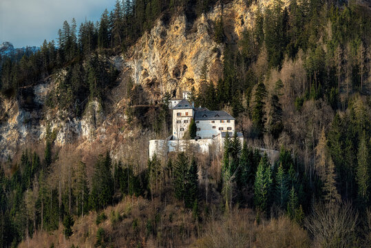 schloss lichtenberg castle in saalfelden am steinernen meer, historic austrian fortress nestled in alpine forest mountainside under golden hour light, medieval architecture in salzburg region
