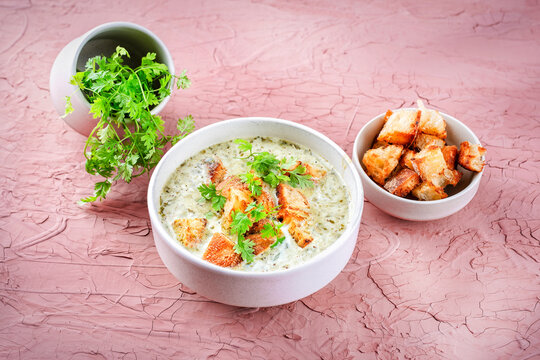 Chervil creamy blend vegetable soup with fresh made roasted whte bread croutons served as close-up in a design bowl