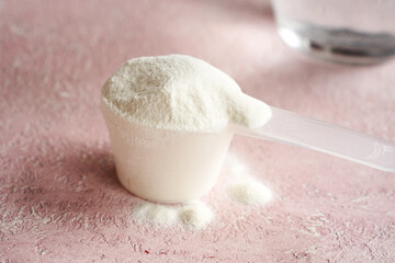 Collagen powder in a scoop with a glass of water