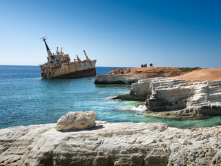 Shipwreck on Rocky Mediterranean Coast.
Rusting shipwreck near a rocky Mediterranean shoreline with white limestone cliffs and clear turquoise water. Scenic coastal landscape under a bright blue sky, 
