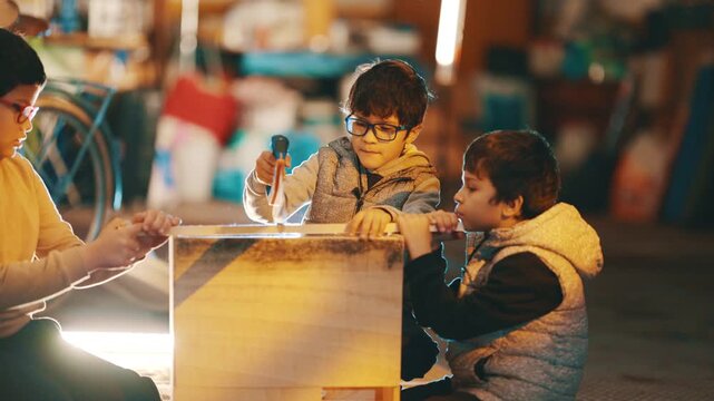 Three young boys building a wooden box together in a garage workshop