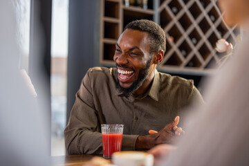 Happy African American man laughing out loud with friends in a cafe.