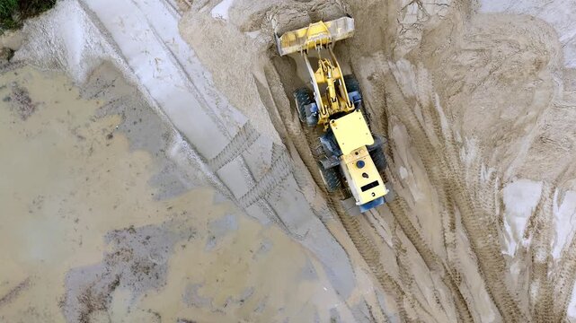 A loader tractor on a sand quarry levels the surface of the sand. High quality 4k footage