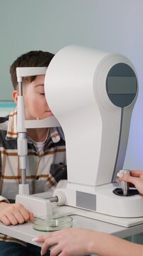 Young boy undergoing eye examination with autorefractor