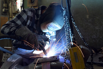 Welder in protective clothing at the workplace in an industrial company in steel construction