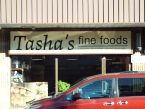 Ottawa, Ontario, Canada-July 19, 2025: The storefront of "Tasha's Fine Foods" features a beige sign with black lettering at 2401 Bank St Unit #7.