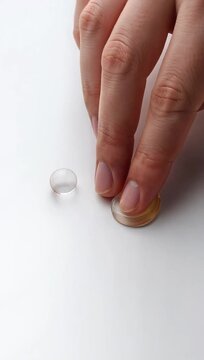 A close-up of a hand placing a contact lens on a white surface, next to a contact lens case, highlighting the process of handling contact lenses.