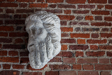 Classical stone sculpture head mounted on brick wall - Italy, Milan