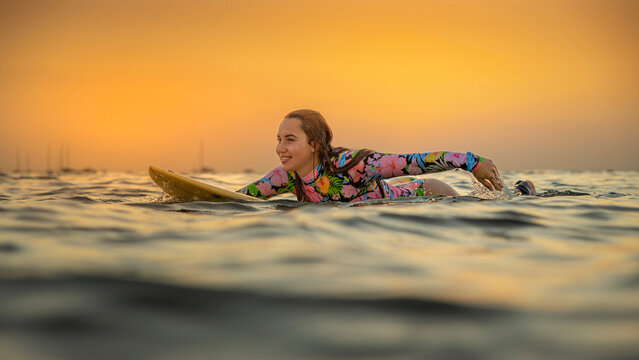 Happy woman surfing at sunset