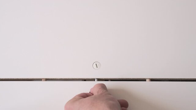 Installation of hidden furniture hardware for internal wall connection in white cabinet