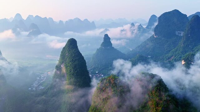 Breathtaking aerial view of karst mountain peaks shrouded in morning mist and clouds in Guilin, China, perfect for travel, nature, and tourism concepts.