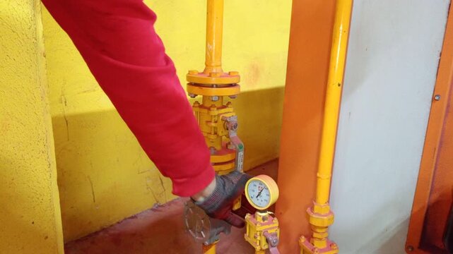 Worker opening natural gas valve of industrial drying oven used for drying fire hose cabinets after chemical cleaning.