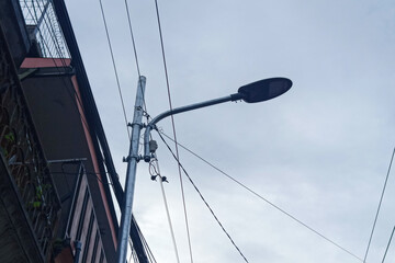 Obraz premium Streetlight pole with wires against a cloudy sky, urban scene
