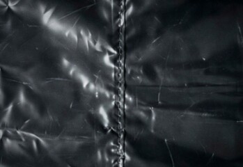 Fototapeta premium Close-up of black glossy quilted jacket seam on wrinkled synthetic leather